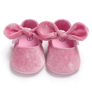 Close-up detail of pink velvet baby princess shoes with large decorative bows