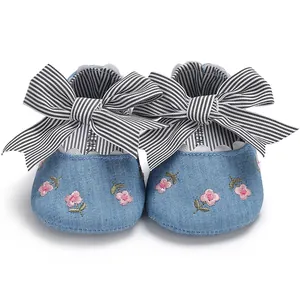 Vue de face de chaussures de princesse pour bébé avec broderie florale et nœud rayé