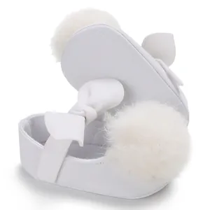 Vue détaillée de chaussures blanches bébé fille avec pompon en fourrure et nœud