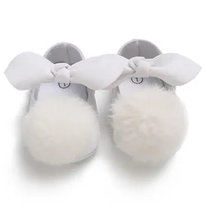 Vue détaillée de dessus de chaussures bébé fille blanches avec nœud et pompon doux