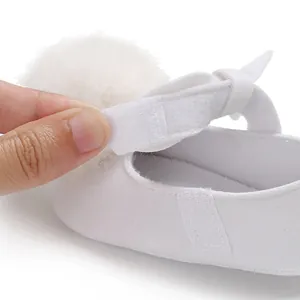 Gros plan de chaussure de princesse bébé blanche avec pompon et sangle velcro