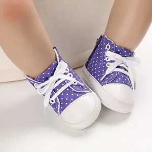 Nahaufnahme lila gepunktete Babyschuhe aus Canvas mit weicher Sohle.