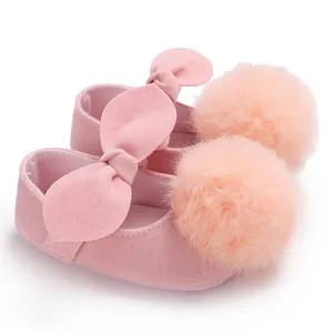 Gros plan de chaussures de princesse roses pour bébé avec pompons doux.