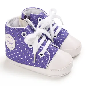 Detailansicht von lila gepunkteten Babyschuhen aus Canvas mit weichen weißen Gummisohlen.