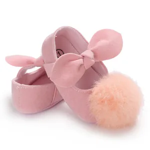 Vue détaillée des chaussures de princesse roses pour bébé avec un gros pompon doux