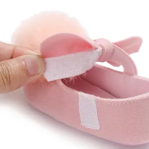 Vue détaillée de la fermeture velcro sur les chaussures de princesse rose pour bébé avec pompon.