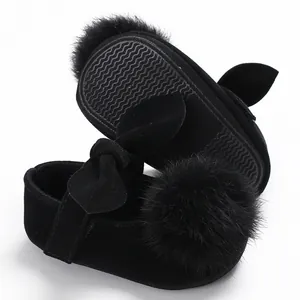 Vue rapprochée de chaussures bébé en velours noir avec pompon doux et nœud