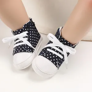 Nahaufnahme von dunkelblauen gepunkteten Baby-Stoffschuhen mit weichen Sohlen.