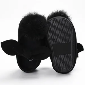 Détail de chaussures de marche noires pour bébé avec pompon en fourrure et nœud élégant