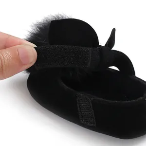 Gros plan d'une chaussure de princesse noire pour bébé avec pompon et fermeture velcro