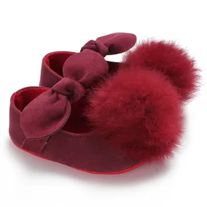 Détail de chaussures de princesse bébé bordeaux avec pompon en fourrure et nœud