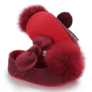 Vue détaillée de chaussures bébé bordeaux avec pompon en peluche et semelle antidérapante.