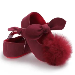 Détail de chaussures princesse bébé bordeaux avec un grand pompon en fausse fourrure
