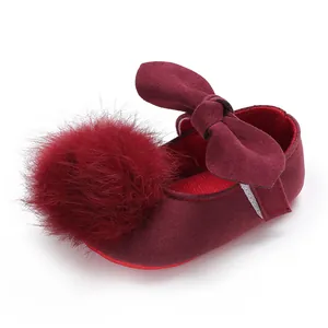 Vue détaillée de chaussures de princesse pour bébé bordeaux avec pompon en fourrure et nœud.