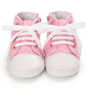 Vorderansicht von rosa gepunkteten Baby-Canvas-Schuhen mit weißen Schnürsenkeln und Reißverschluss