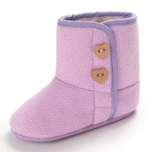 Detailweergave van roze gebreide baby sneeuwlaarzen met hartjesknopen en fleece voering