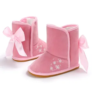 Nahaufnahme der rosa Baby-Schneestiefel mit Schleife und Schneeflockenstickerei