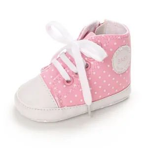 Nahaufnahme eines rosa gepunkteten Baby-Leinenschuhs mit weißen Schnürsenkeln und Reißverschluss