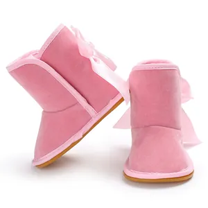 Nahaufnahme rosa Baby-Schneestiefel für Mädchen mit Satinschleifen und rutschfester Sohle.