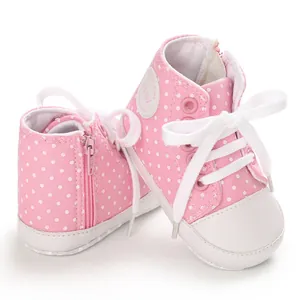 Detail der rosa gepunkteten Baby-Leinenschuhe mit weißen Schnürsenkeln und Reißverschluss