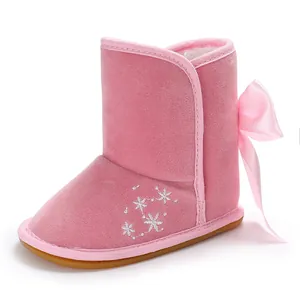 Nahaufnahme von rosa Baby-Schneestiefeln mit dekorativer Schleife und Sternstickerei.