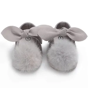 Gros plan de chaussures de princesse pour bébé avec grand nœud et pompon en fourrure