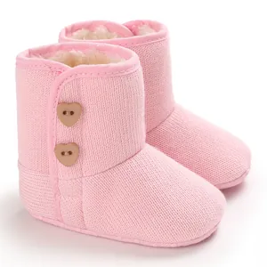 Detailweergave van roze gebreide babysneeuwlaarzen met hartknopen en warme voering
