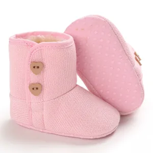 Detail van roze gebreide baby snowboots met pluche voering en hartknopen
