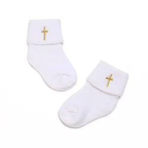 Detail view of white cotton baby socks with elegant gold cross embroidery for infants