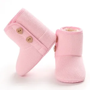 Roze gebreide baby sneeuwlaarzen met warme fleece voering en hartvormige knopen.