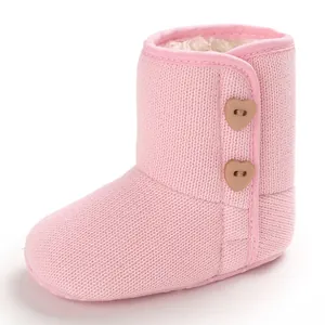 Detailopname van roze gebreide babysneeuwlaars met fleecevoering en hartjesknopen.