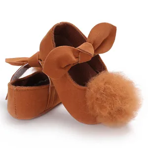 Gros plan de chaussures de marche bébé fille avec nœud et pompon marron