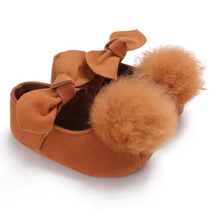 Vue détaillée de chaussures de marche pour bébé fille en suédine marron avec pompons et nœuds