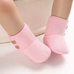 Detailopname van warme roze gebreide baby winterlaarzen met schattige hartvormige knopen
