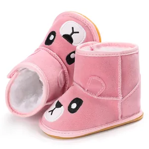 Close-up of pink baby winter boots with warm white fleece lining and cartoon face