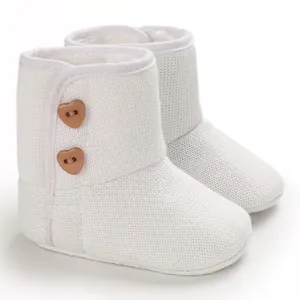 Gedetailleerd overzicht van wit gebreide baby sneeuwlaarzen met fleece en hartknoppen