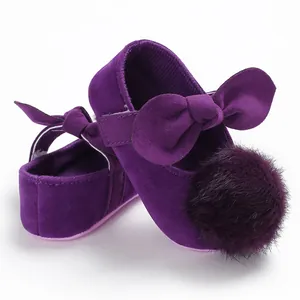 Vue détaillée de chaussures bébé violettes avec pompon en fourrure et nœud décor