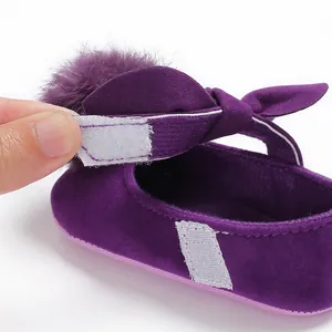 Détail d'une chaussure bébé fille violette avec pompon en fourrure et fermeture velcro