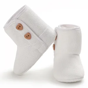 Detailopname van witte gebreide baby-winterlaarzen met houten hartknopen en fleece voering