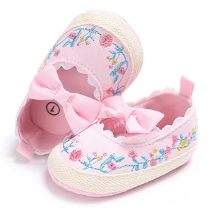Detailopname van roze geborduurde babyschoentjes voor meisjes met zachte zool en strik