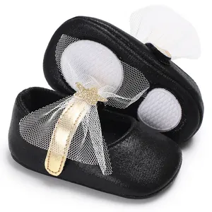Nahaufnahme schwarzer Baby-Prinzessinenschuhe mit Goldstern und weißer Tüllschleife