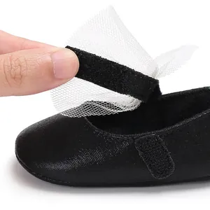 Nahaufnahme schwarzer Baby-Prinzessinenschuh aus PU mit weißer Tüllschleife und Klettverschluss