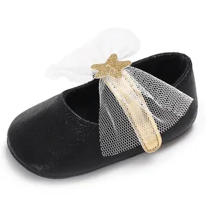 Detail eines schwarzen Baby-Prinzessinenschuhs mit weißer Tüllschleife und Goldstern