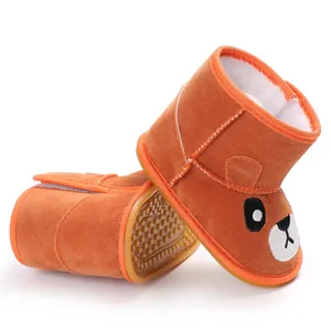 Detail view of orange baby winter boots with cartoon face and non-slip rubber sole