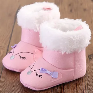 Close-up of pink baby snow boots with fluffy white collar and bow detail.