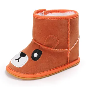 Close-up of orange baby winter boot with cartoon bear design and thick fur lining.