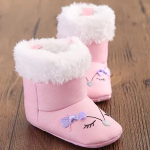 Close-up of pink baby snow boots with white fur trim and purple bow detail