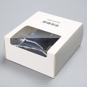 Detalle de zapatos cálidos para bebé en una caja de regalo blanca con ventana transparente.