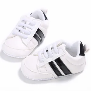 Vista detallada de zapatillas blancas para bebé con rayas negras y suelas blandas