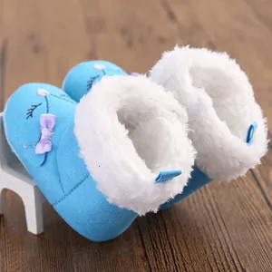Detail view of blue baby winter snow boots with white faux fur lining and purple bow.